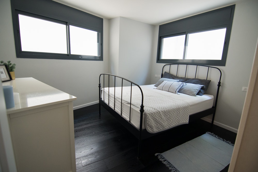 חדר אירוח עם מיטת ברזל ישנה.