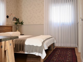 חדר שינה עם פרקט עץ, שטיח אדום ווילון לבן