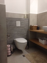 חדר שרותיים עם מדפי עץ דקורטיבים והתקנת כיור וסניטריה